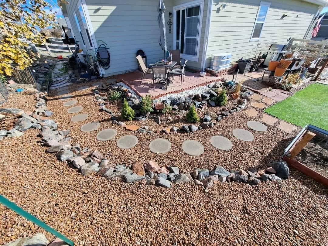 Gravel bed with white stone border, pavers and planted shrubs near house foundation