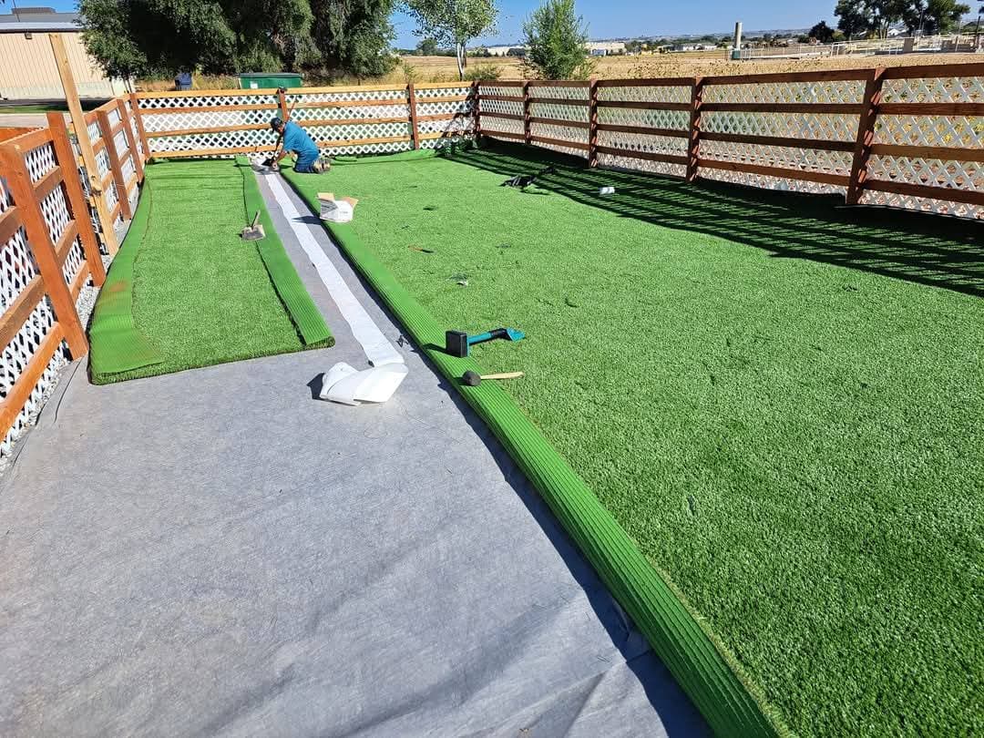 Worker installing artificial turf along residential lawn edge