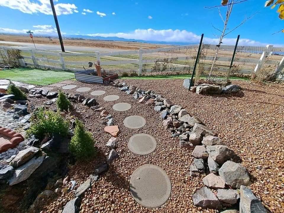 Stone pathways, gravel, rock borders and planted vegetation in sloped yard