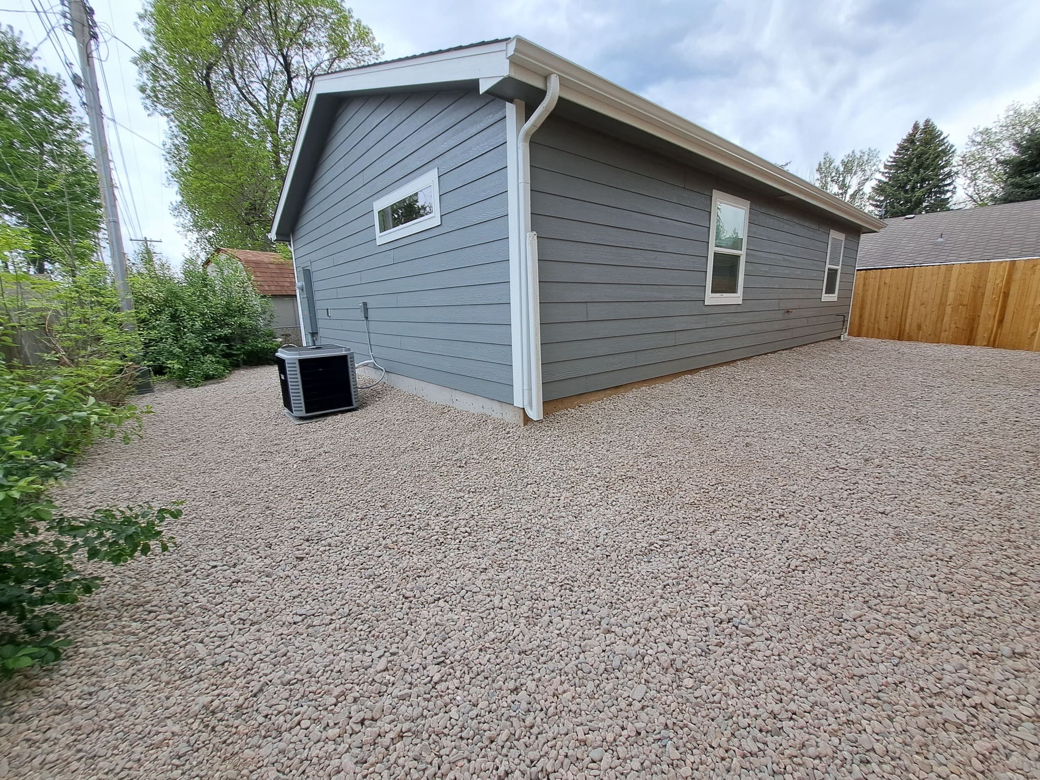 Completed small residential building with siding and gravel parking area