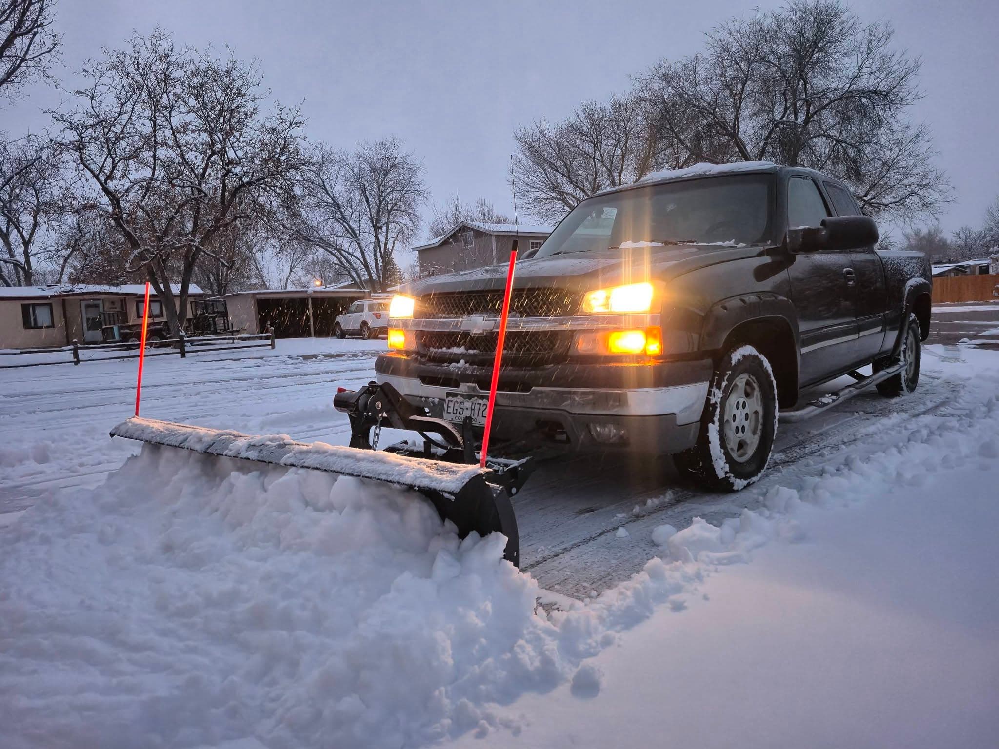 Pickup truck with snow plow clearing driveway